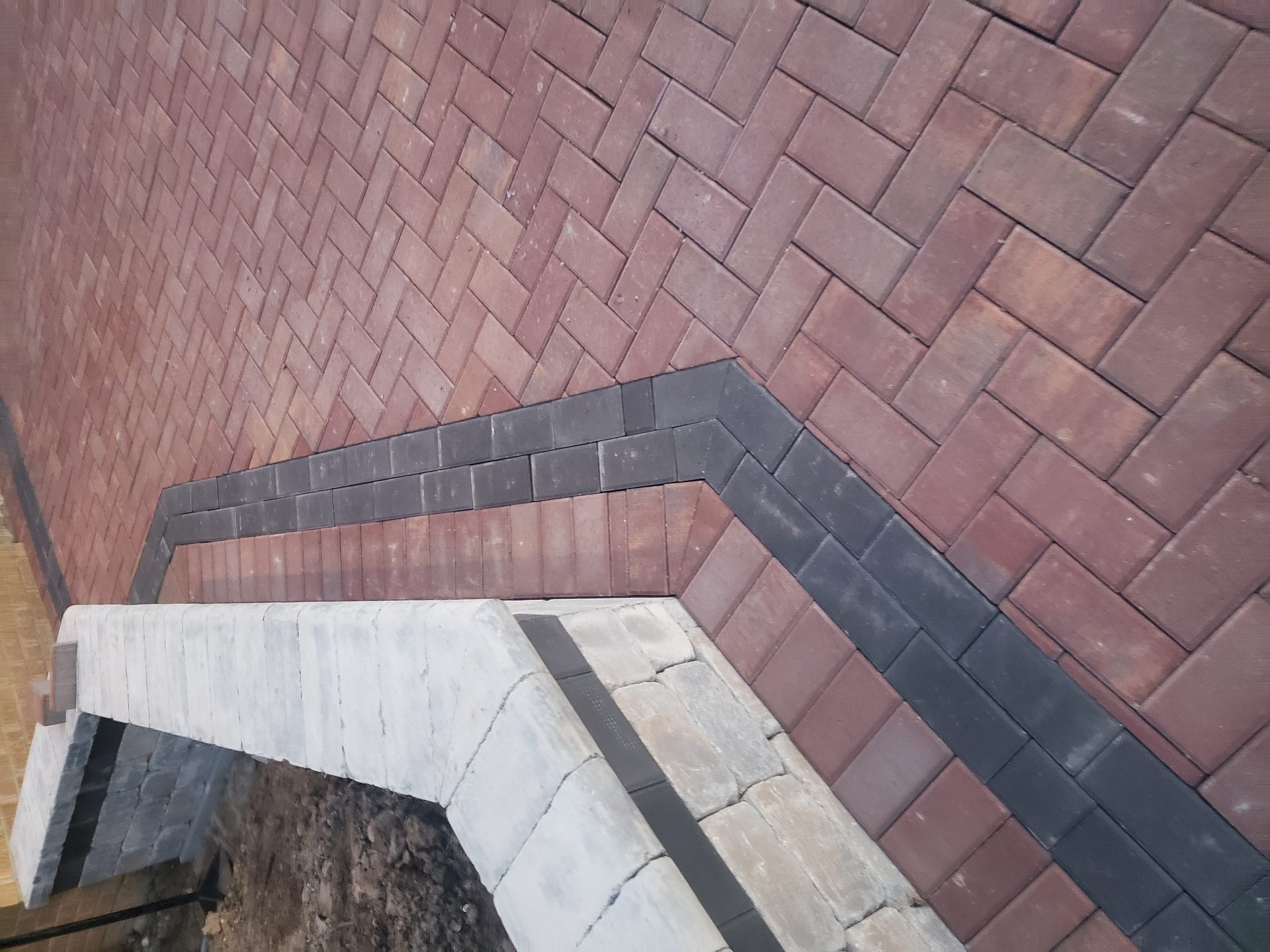Burgundy herringbone brick paver patio with charcoal border and stone steps