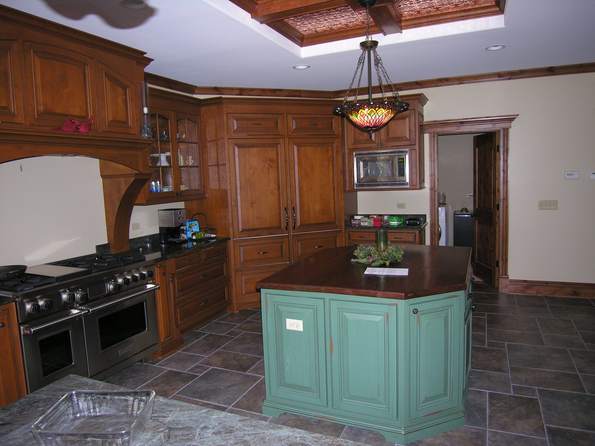 Kitchen with coffered ceiling, stone hood, and custom cabinetry