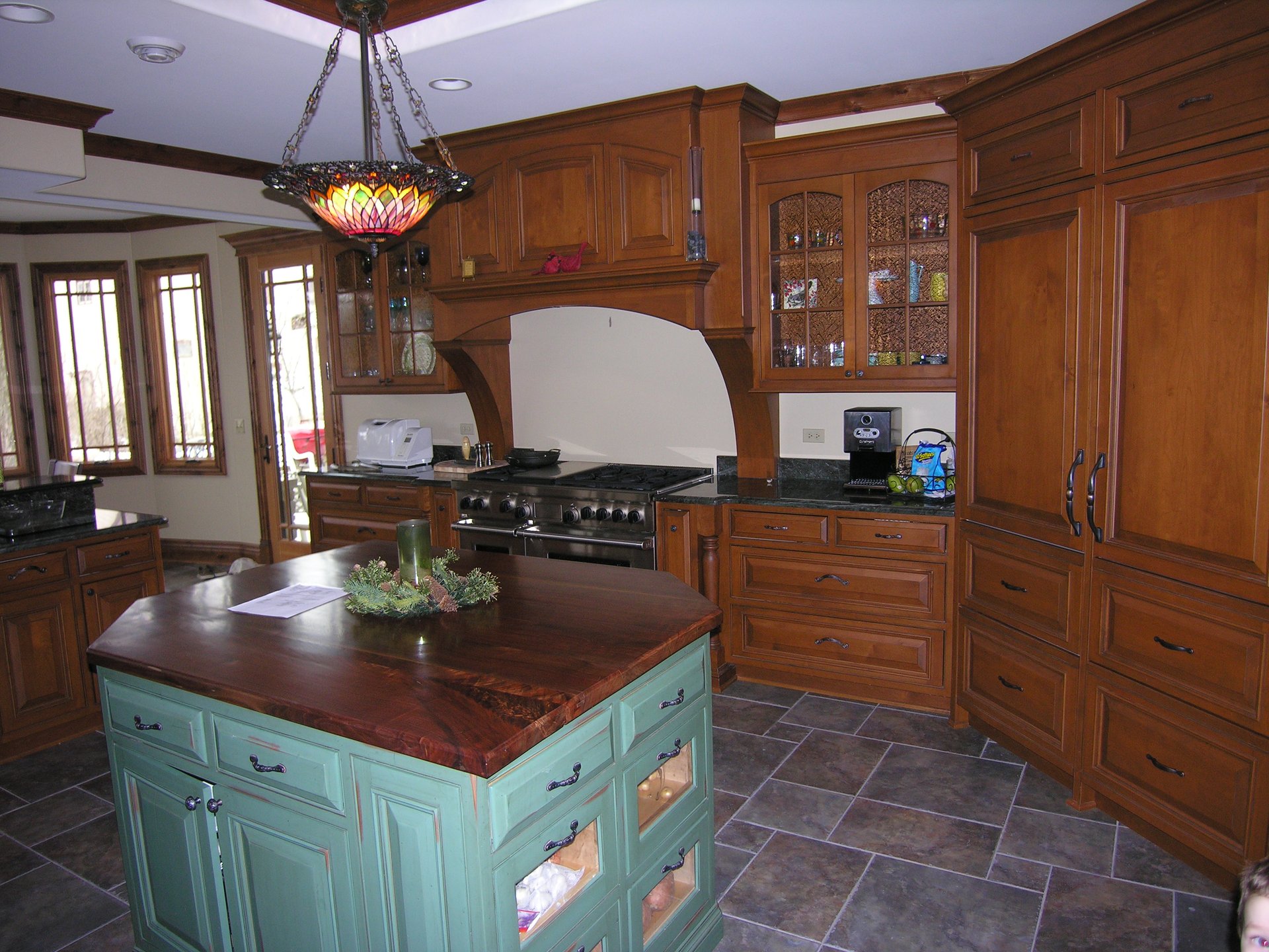 Custom kitchen with green center island, walnut counter, and Wolf range