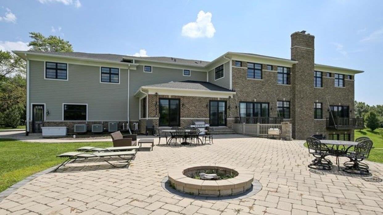 Custom brick two-story home rear exterior with paver patio and stone fire pit